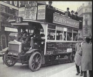 Bus with volunteer driver and police escort 1926. The police escort is sitting on the exterior of the front of the double decker bus.